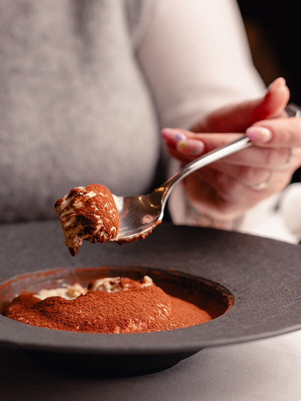 Female diner enjoying a tiramisu.